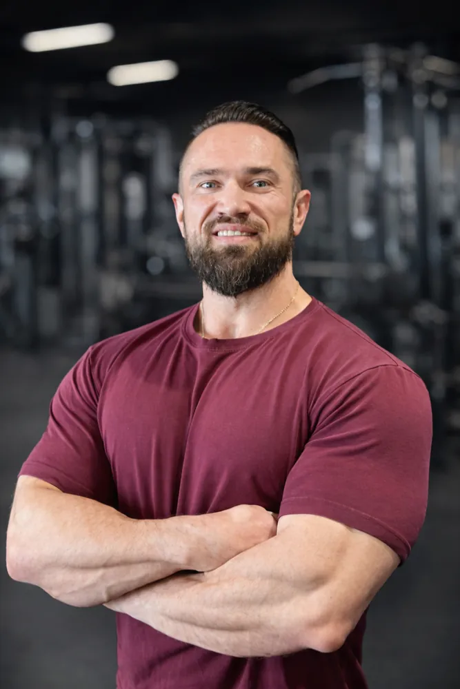 Coach Artem Piari, arms crossed and smiling in the gym